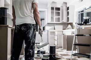 a person painting kitchen cabinets